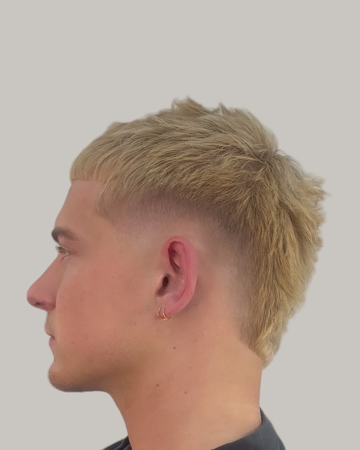 Man with a blond textured crop and a long fringe, seen in profile