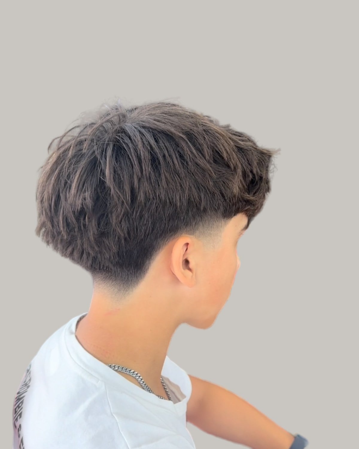 Man with a messy textured crop and a low taper fade, seen from behind