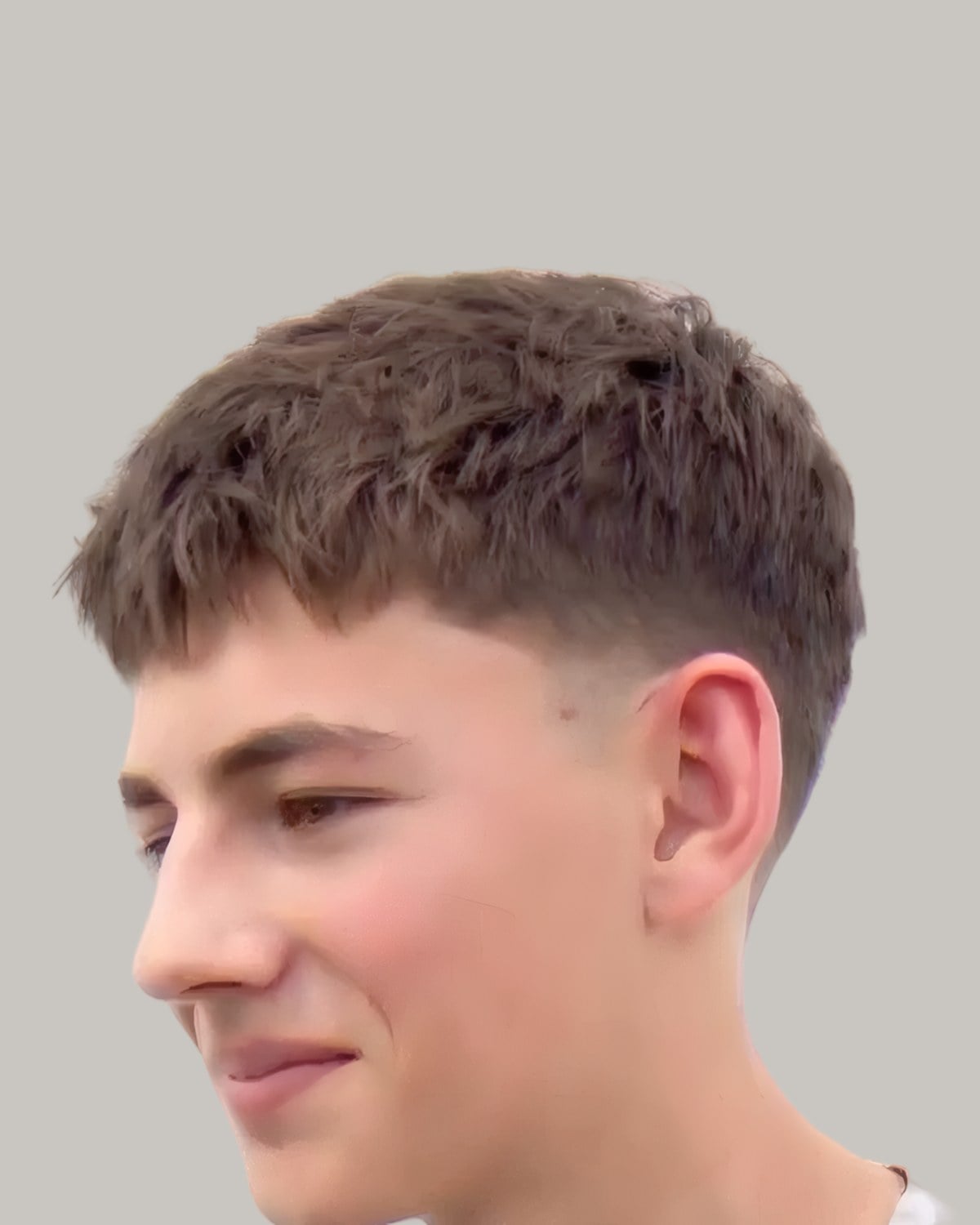 Young man with a brown textured crop and a low taper, looking to the side