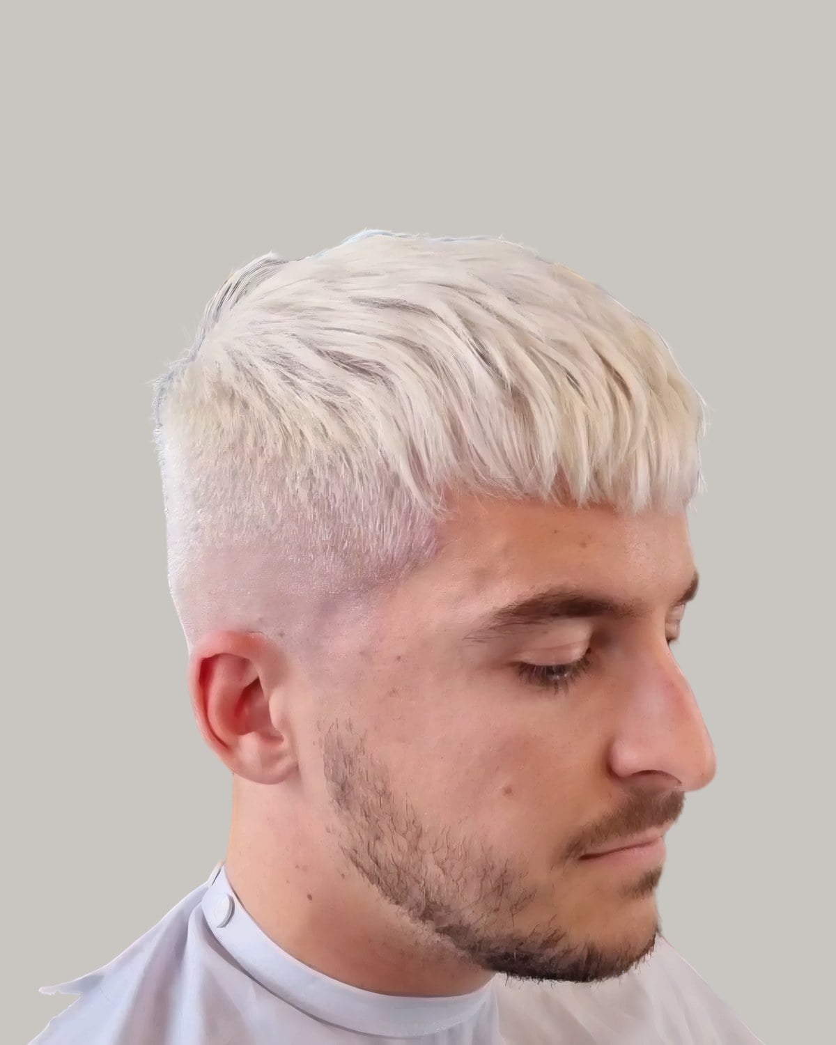Man with a platinum French crop and a skin fade, looking down