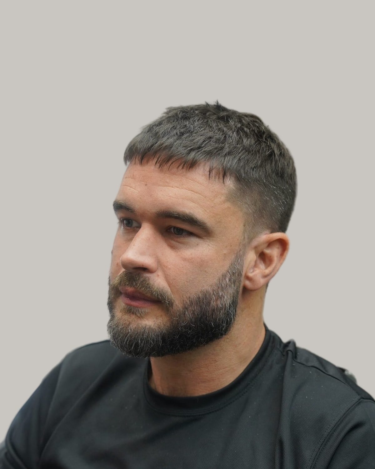 Man with a short textured crop and a trimmed beard, looking to the side