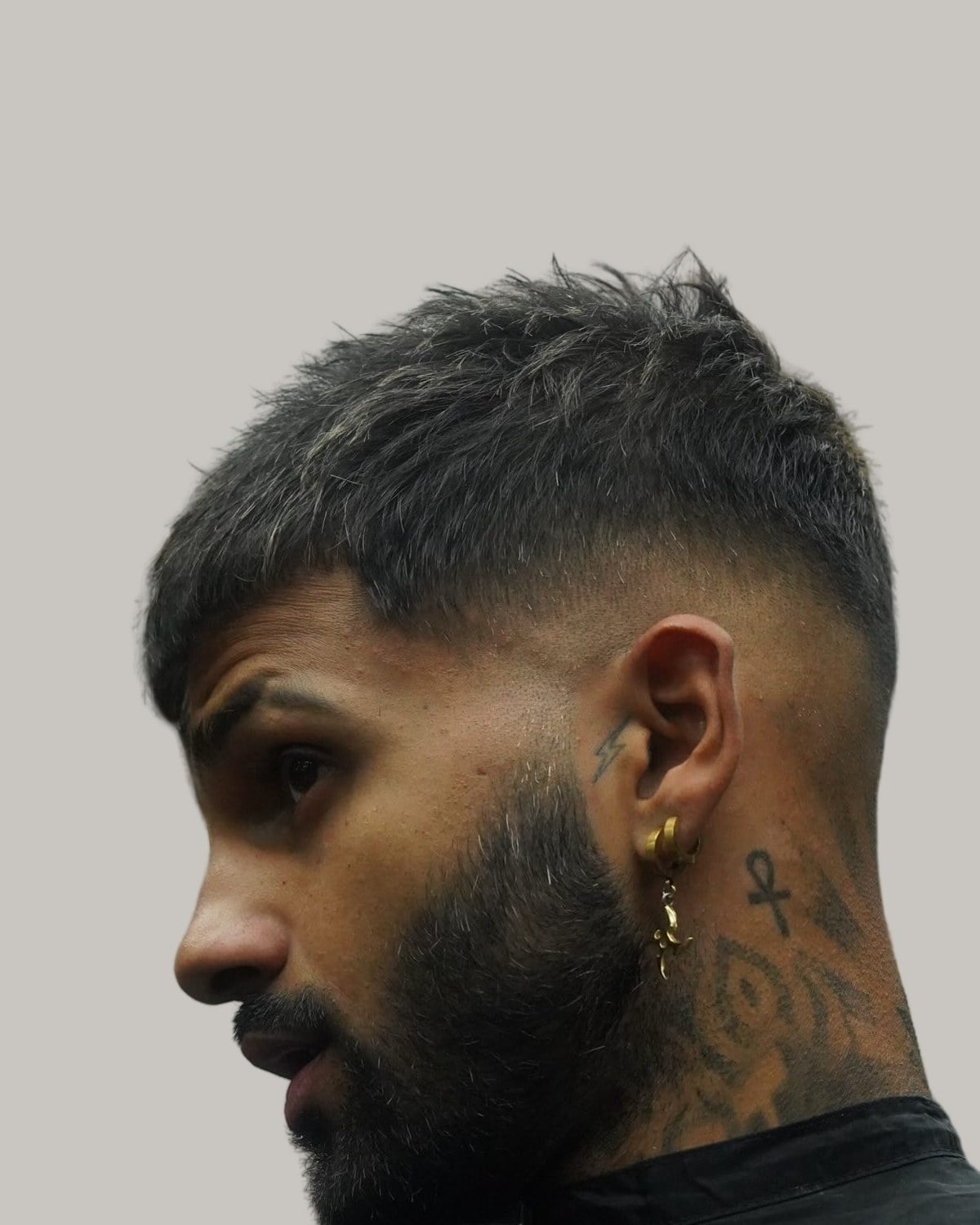 Bearded man with a textured French crop and a skin fade, seen in profile