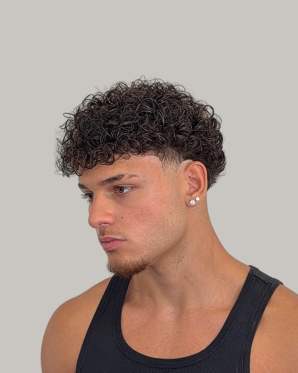 Man with short tight curls, a low taper and a line-up, in a black tank top