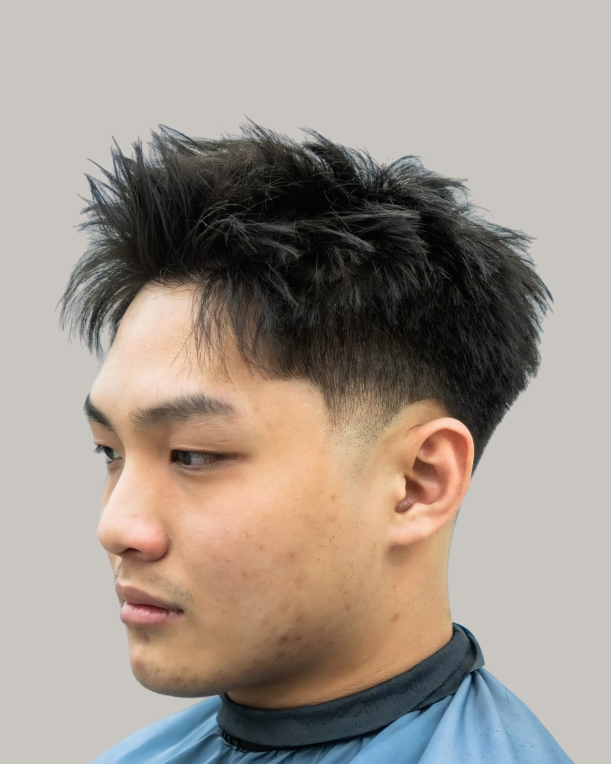 Asian man with a spiky, lifted textured fringe and a low taper