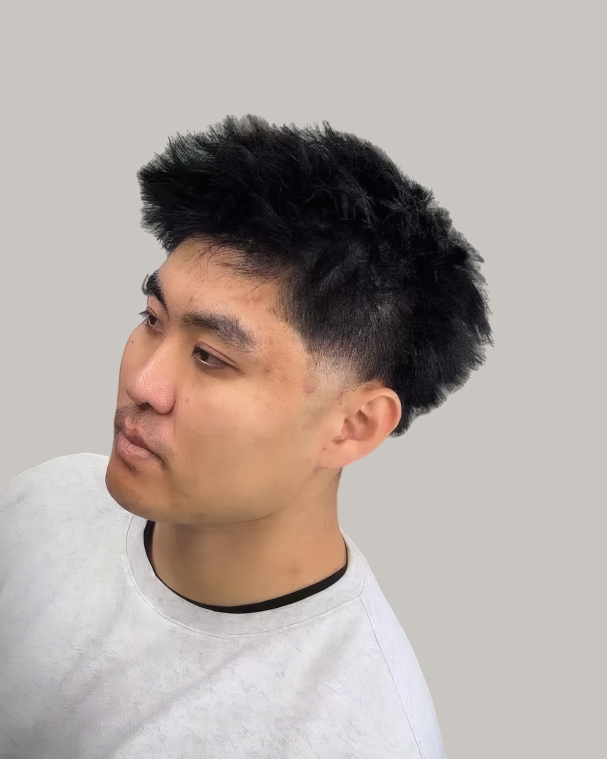Asian man with a spiky textured fringe blown up and out, and a taper