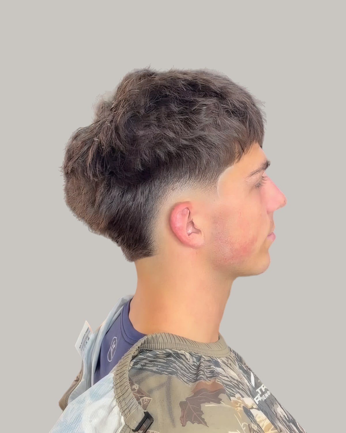 Man with a textured fringe and a burst fade, seen from the side