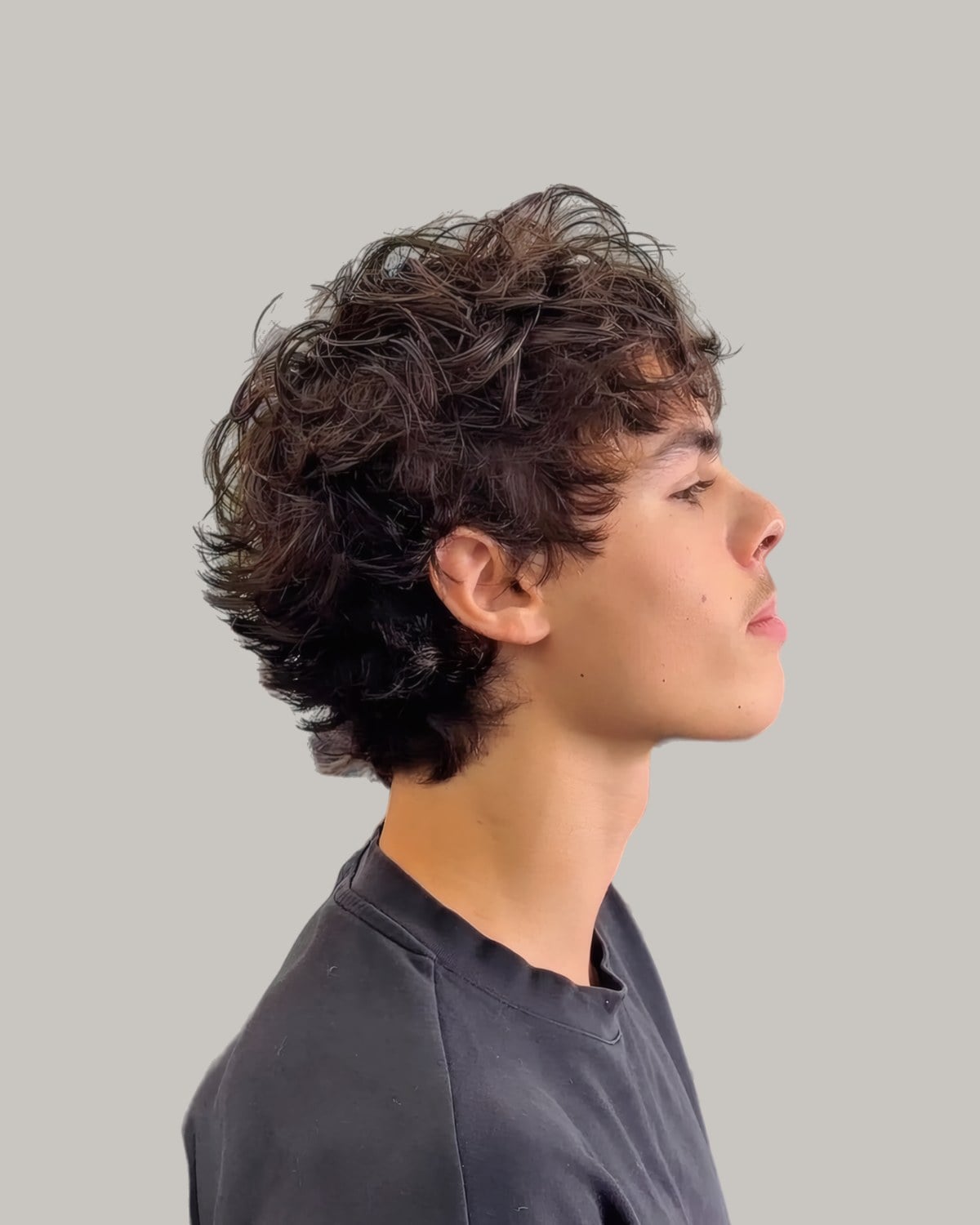 Young man with a curly fringe falling forward, seen in profile