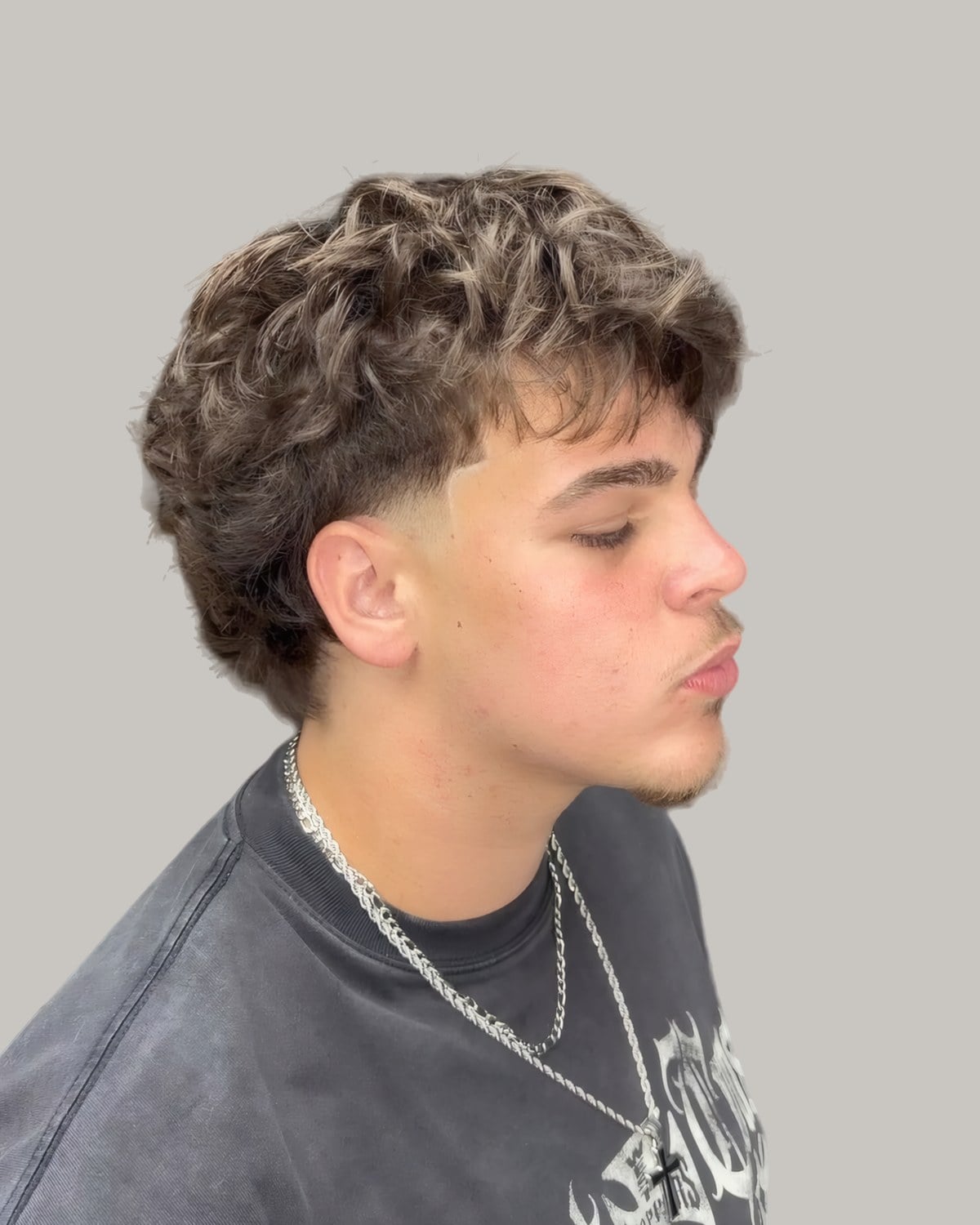 Young man with a curly textured fringe and a low taper, seen in profile