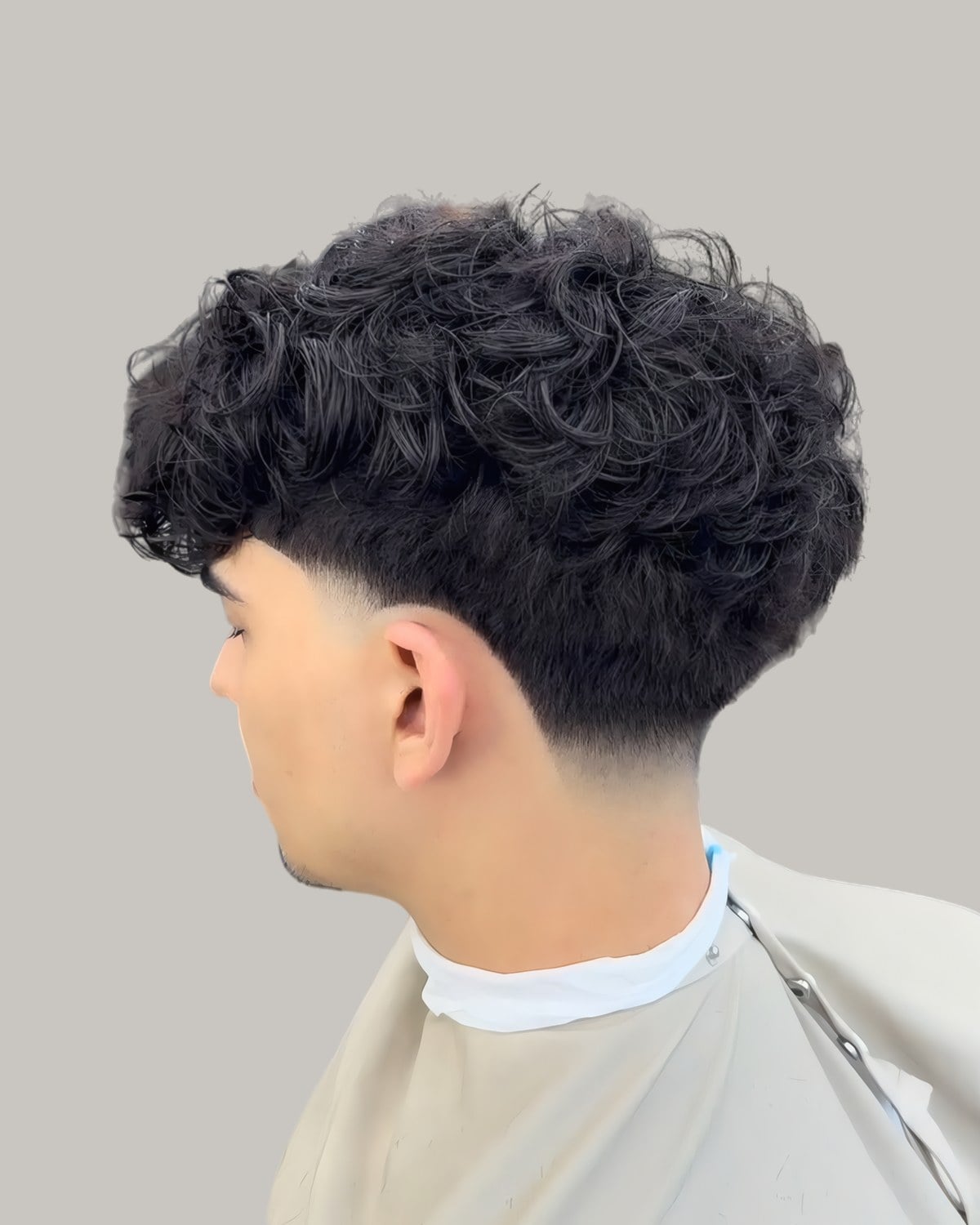 Man with curly hair and a taper, seen from behind at an angle