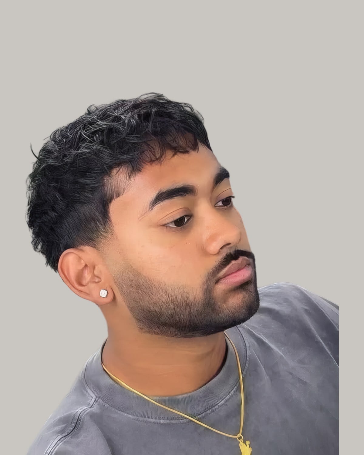 Bearded man with a curly textured fringe and a fade, looking to the side