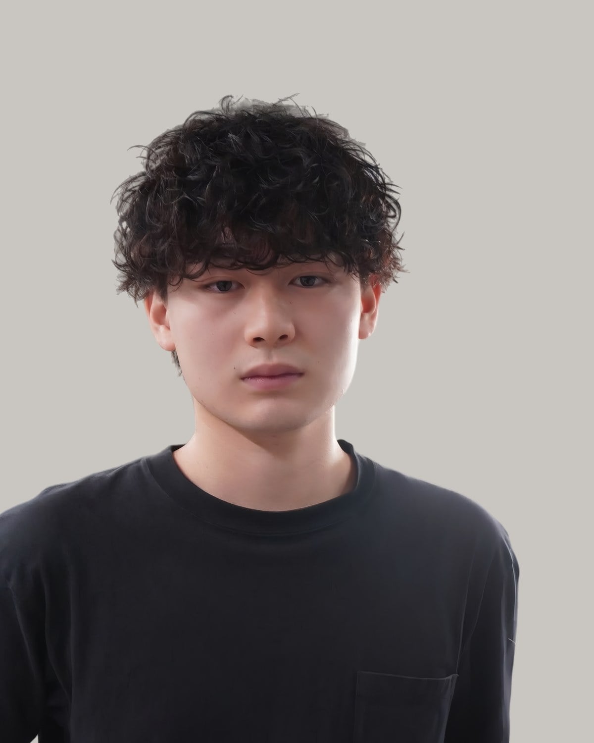 Young Asian man with a dense curly fringe, facing the camera