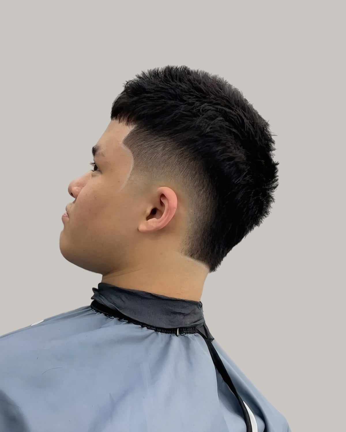 Young man with a textured fringe and a high taper, seen in profile