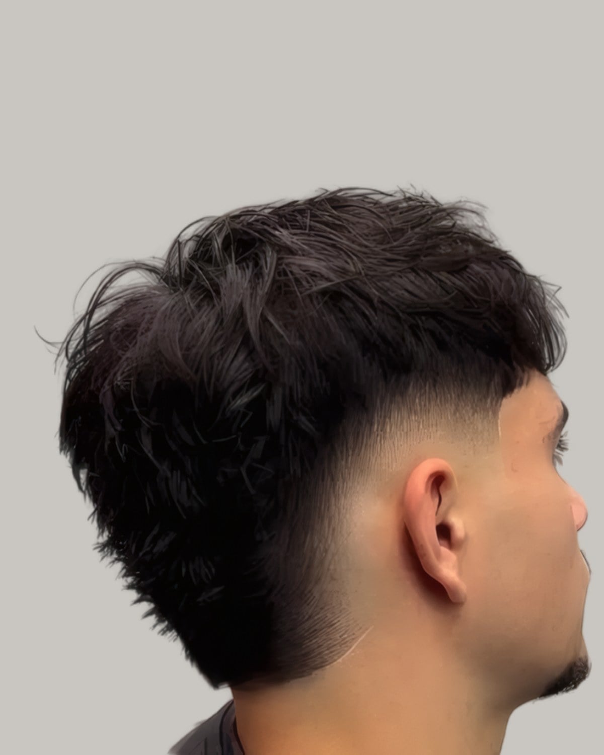 Man with a dark textured top and a low taper fade, seen from behind at an angle