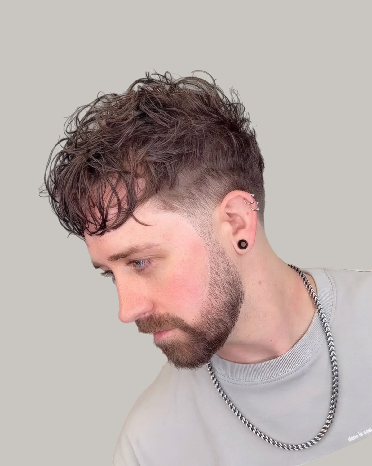 Bearded man with a messy curly fringe, looking down