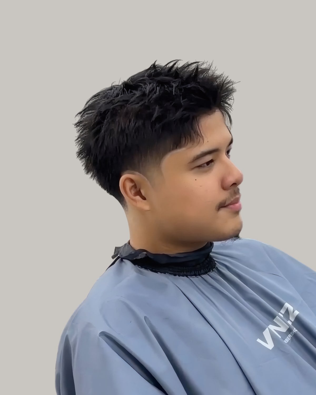 Young man with a spiky textured fringe and a mid taper, seen at an angle