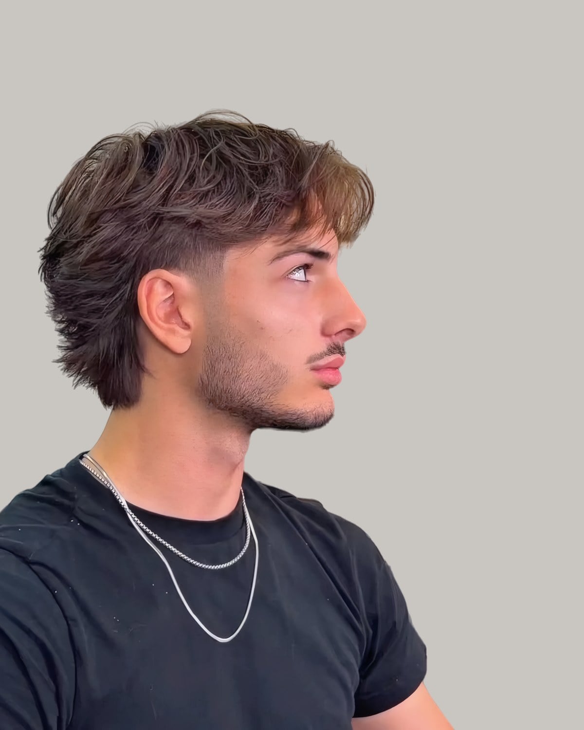 Man with a textured fringe mullet and a taper, seen from the side