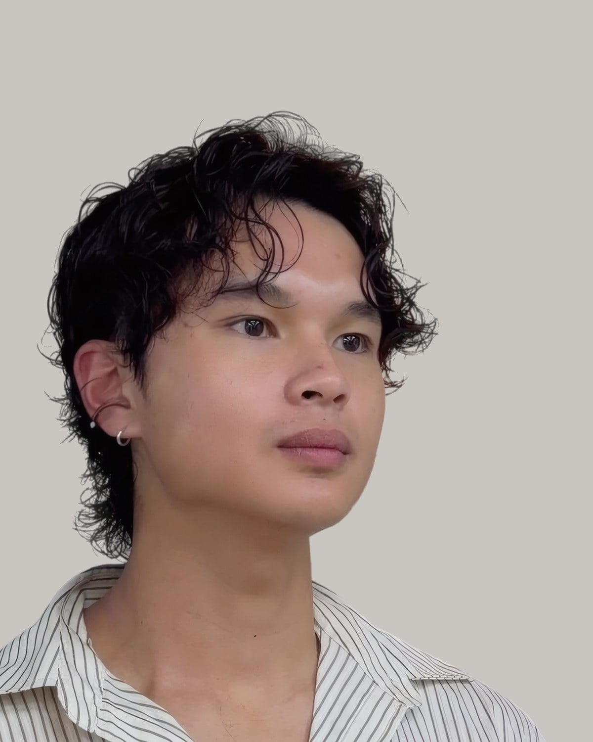 Young man with a permed curly fringe, looking to the side