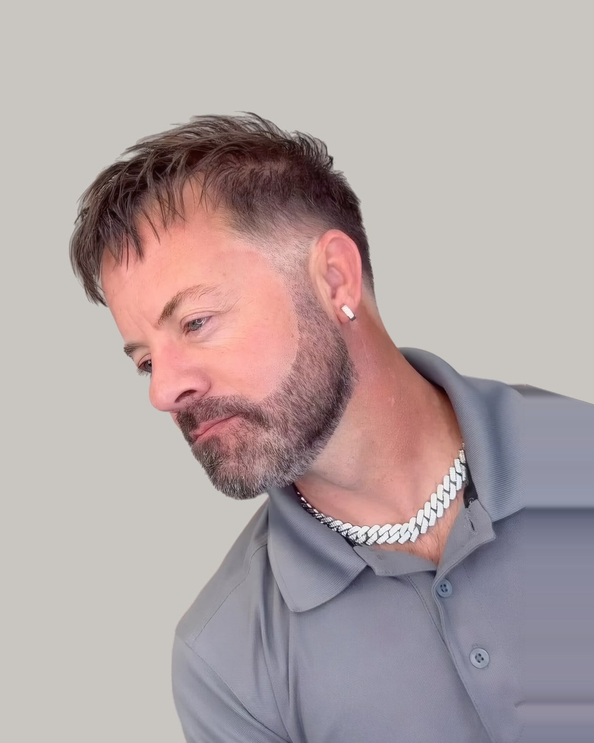 Bearded man with a short textured fringe brought forward, looking to the side