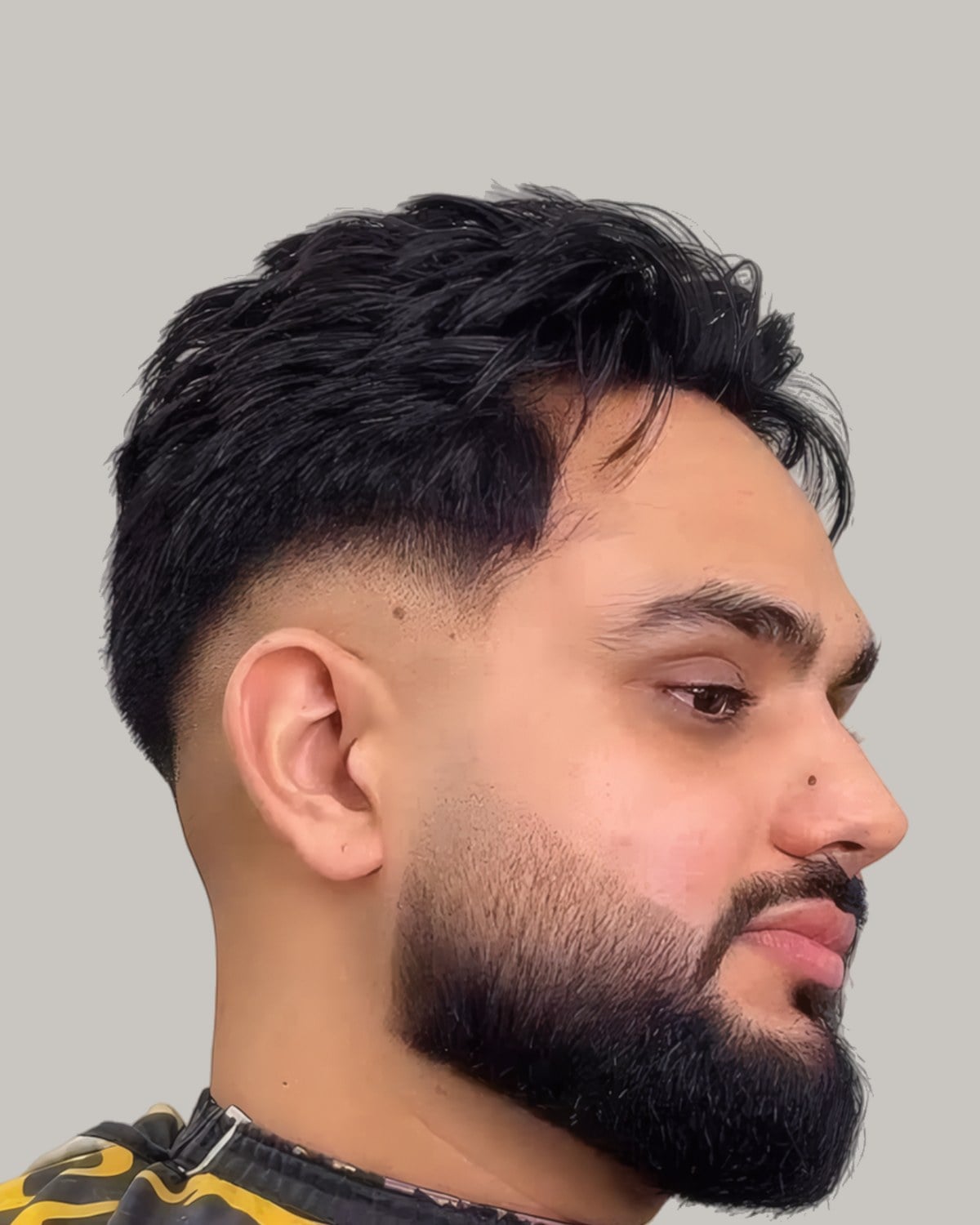Bearded man with a short textured fringe and a taper, seen at an angle