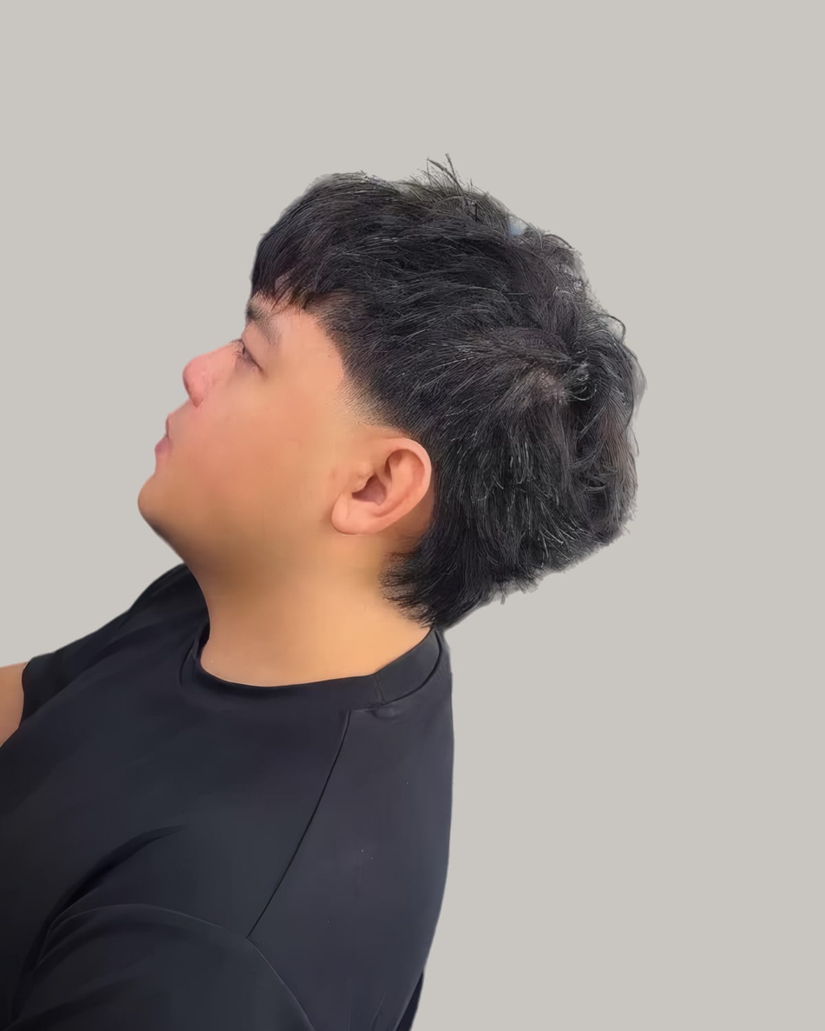 Young man with straight, spiky textured hair and a taper, seen in profile