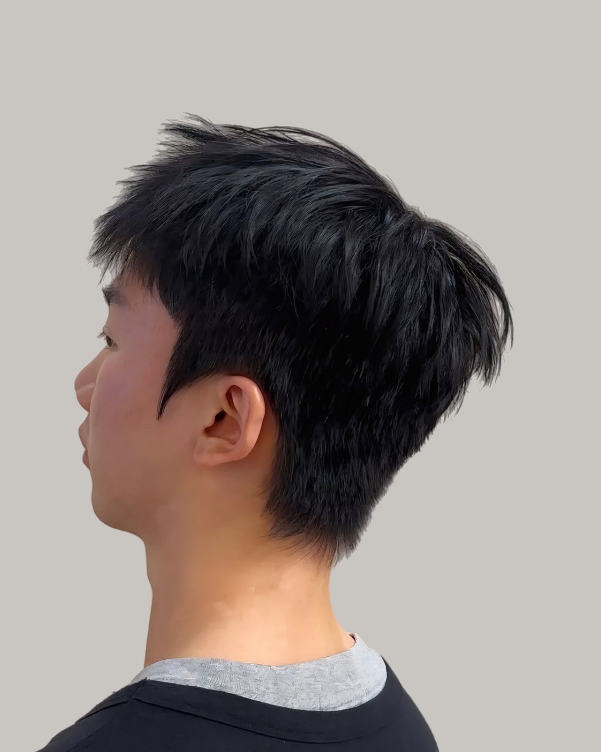Young Asian man with a straight textured top and a taper, seen from behind at an angle