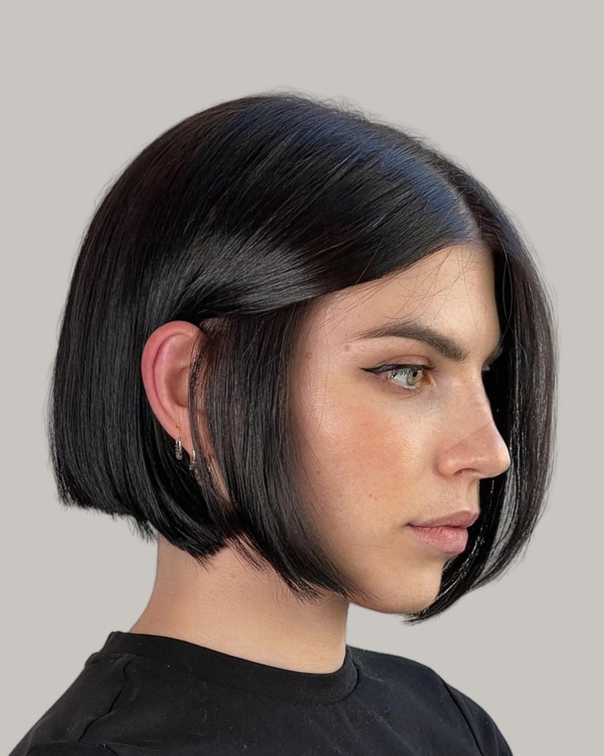 Woman with a glossy black blunt bob, seen in profile