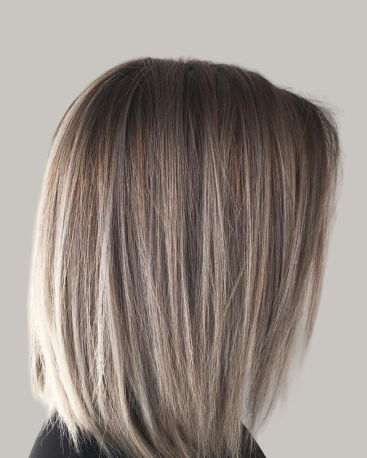 Woman with an ash-blonde blunt lob, seen from behind at an angle