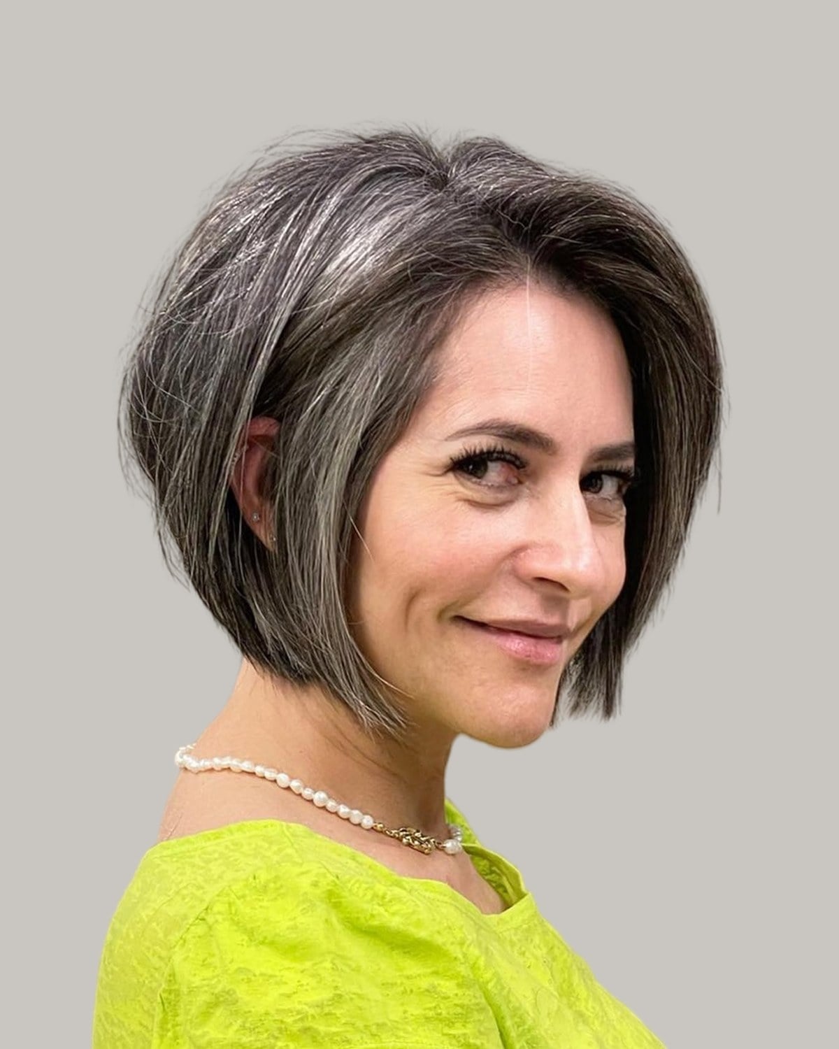 Smiling woman with a gray and brown bob and a deep side part
