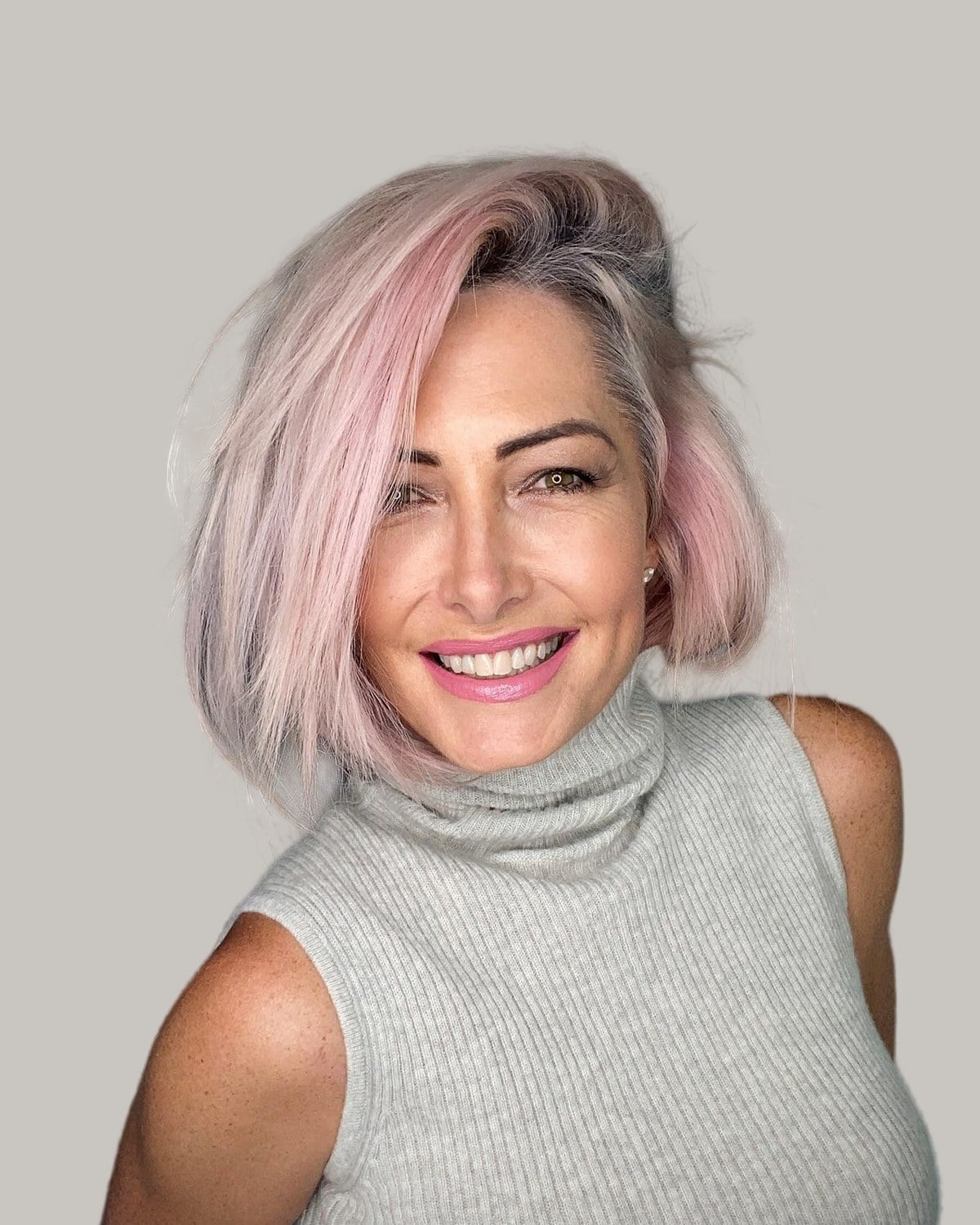 Smiling woman with a pink and silver choppy bob, facing the camera