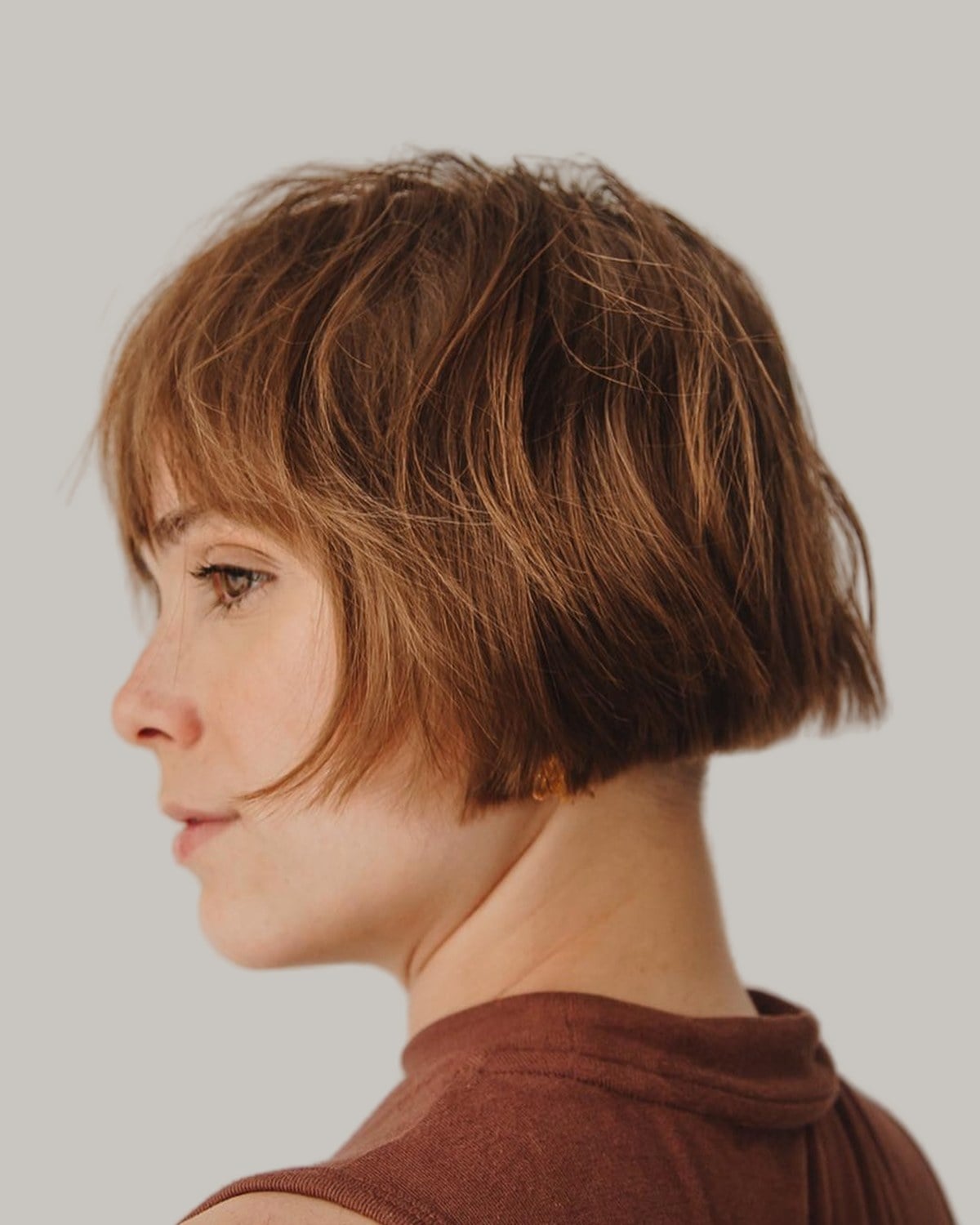 Woman with a copper cropped French bob, seen in profile