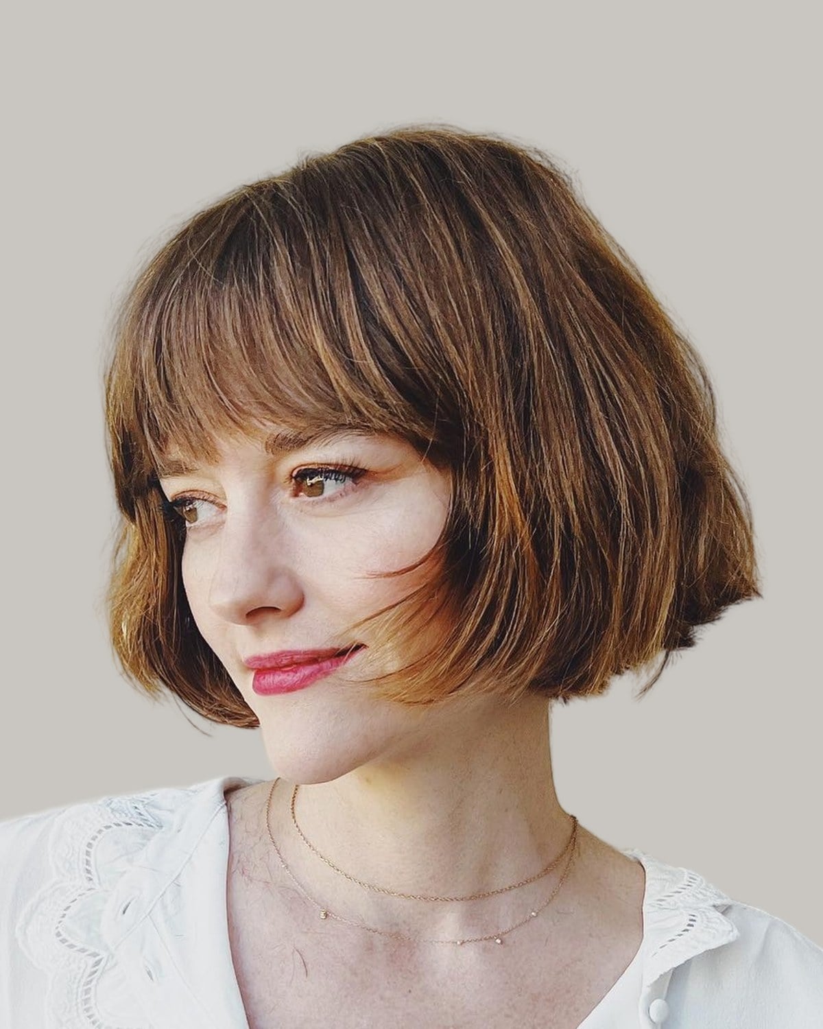 Woman with a brunette French bob and soft bangs, in three-quarter view