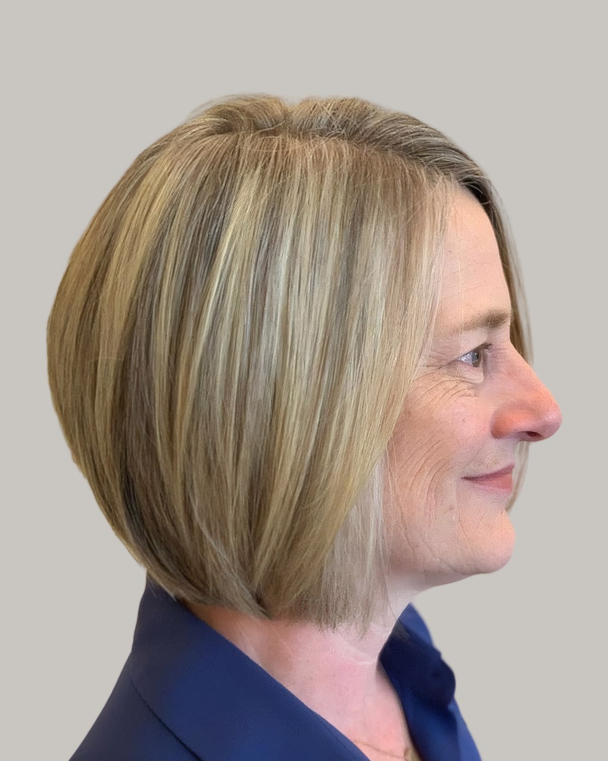 Smiling woman with an ash-blonde graduated bob, seen in profile