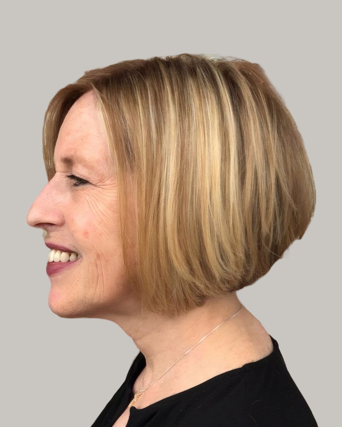 Smiling older woman with a golden inverted bob, seen in profile
