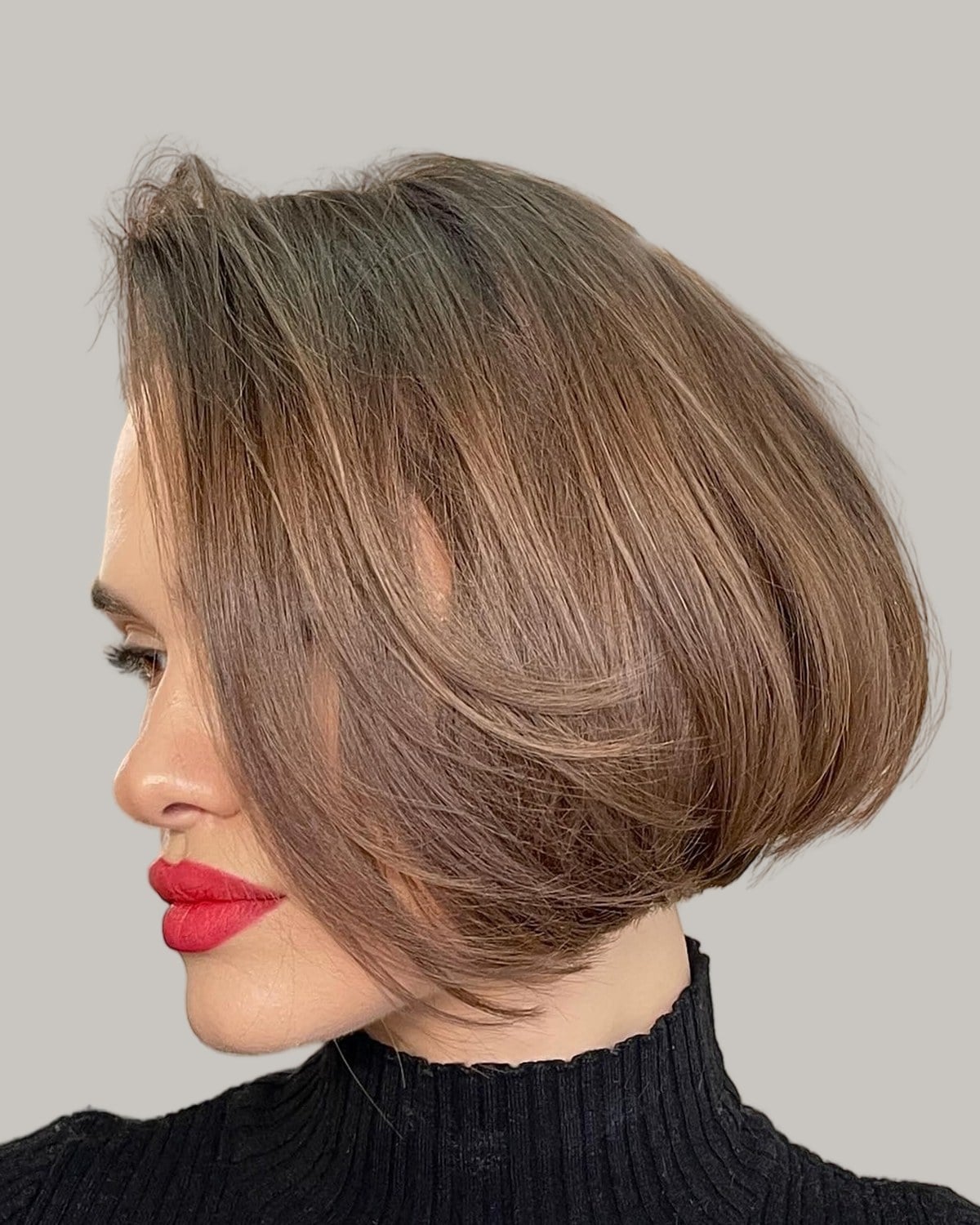 Woman with a light brown rounded bob and red lipstick, seen in profile