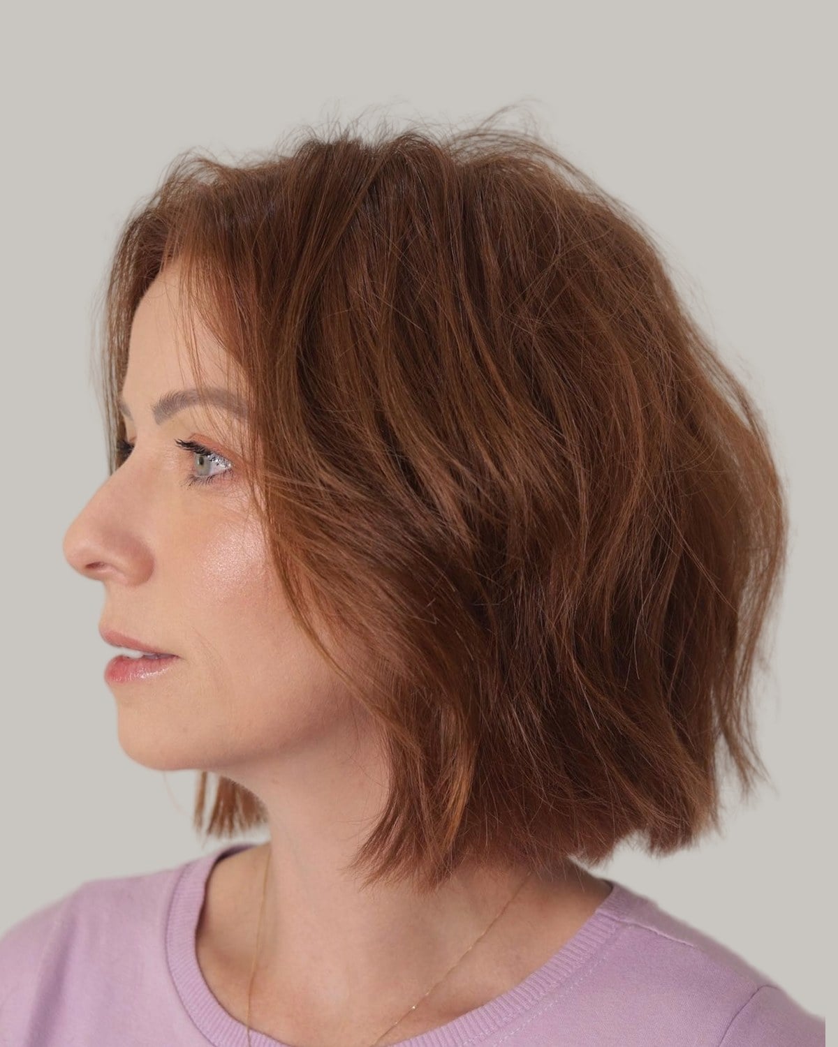 Woman with a copper wavy bob, seen in profile