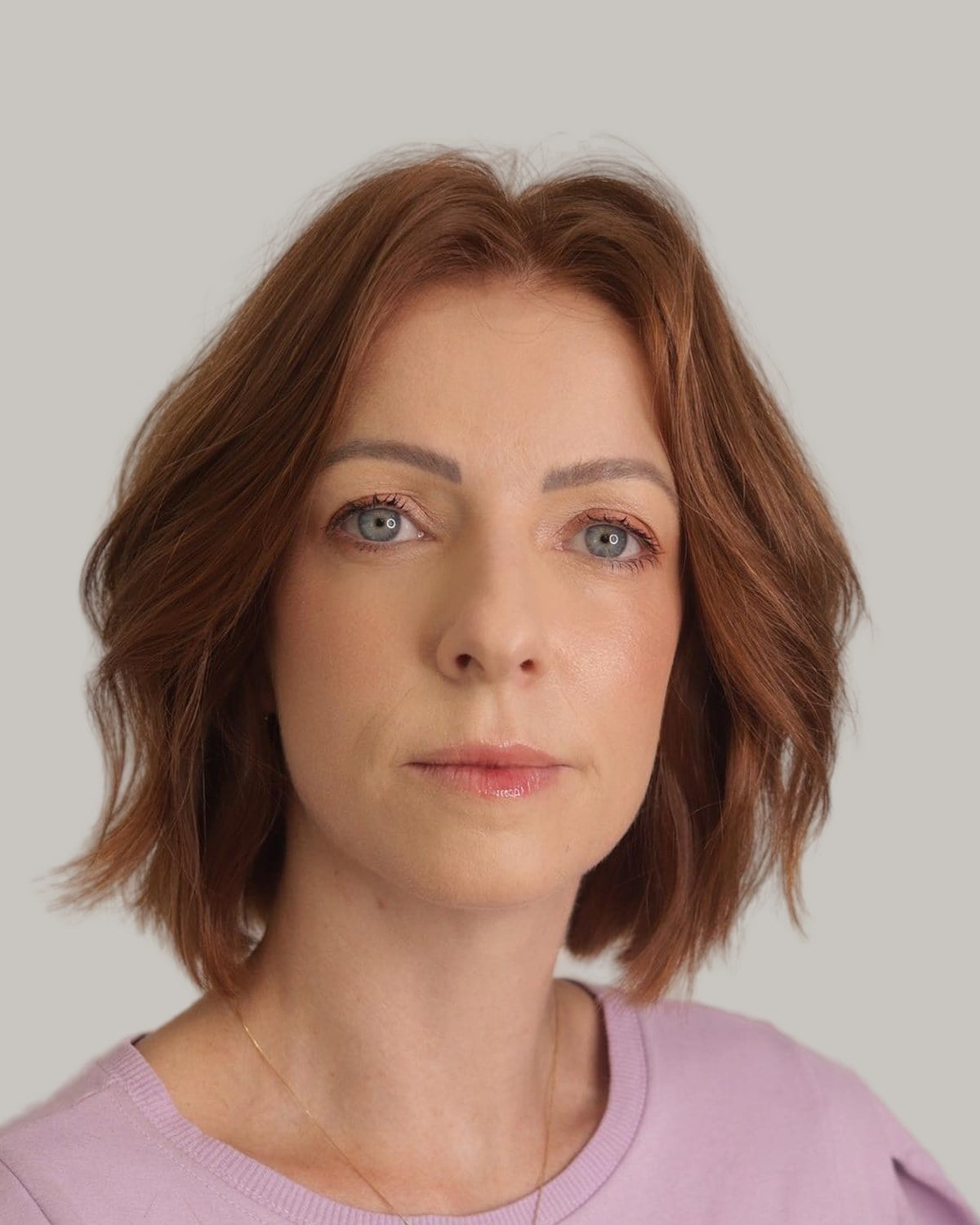 Woman with a copper bob and soft waves, facing the camera