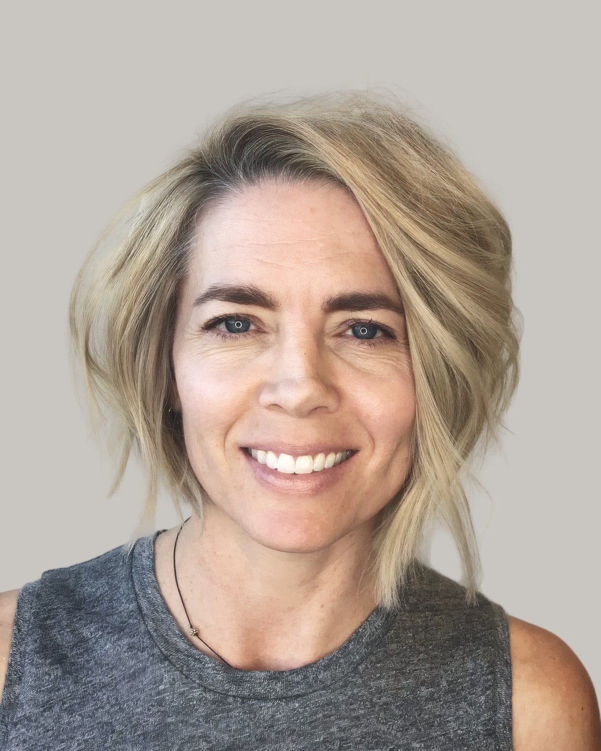 Smiling woman with a blonde layered bob and a side part, facing the camera