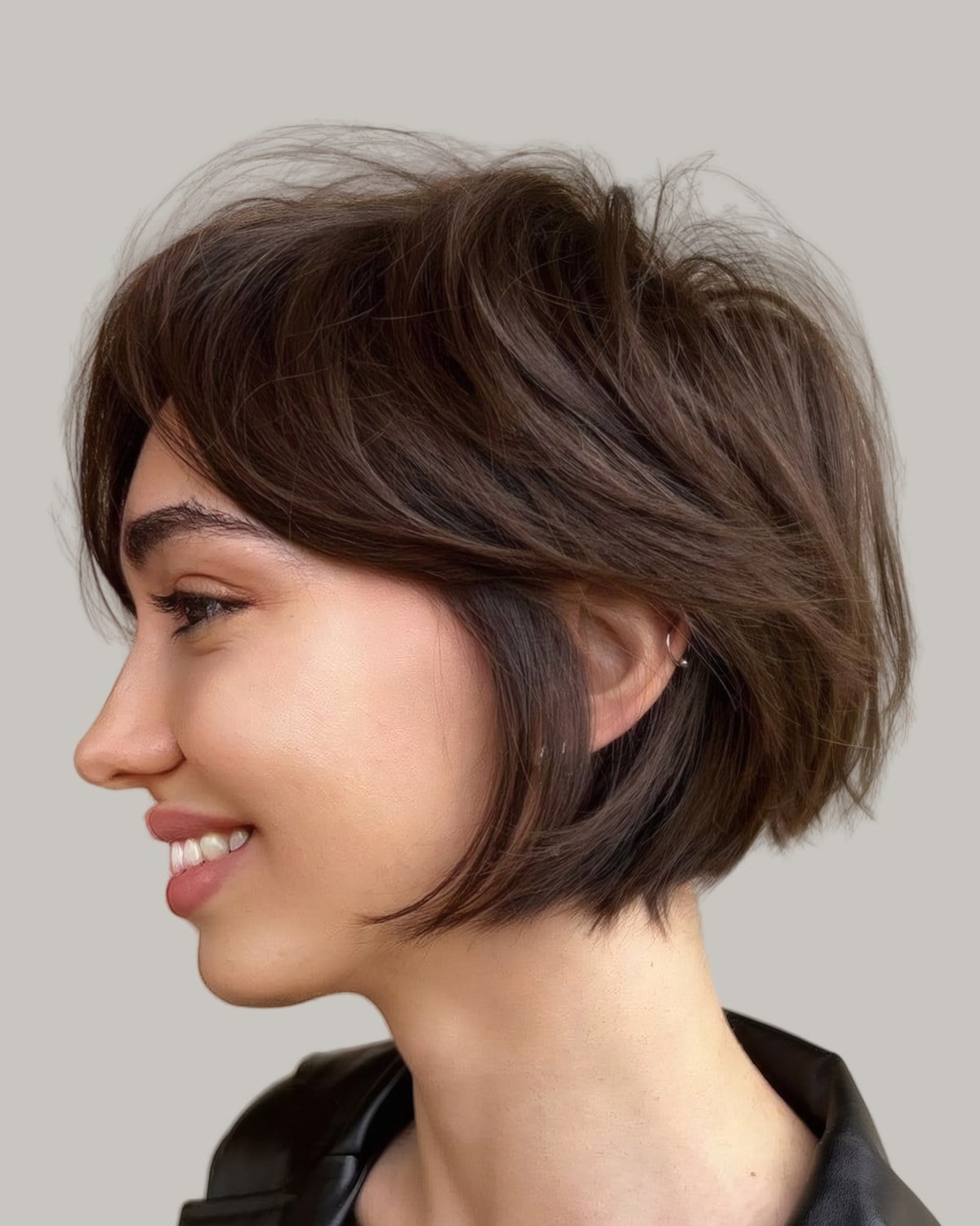 Smiling woman with a brown pixie bob, seen in profile
