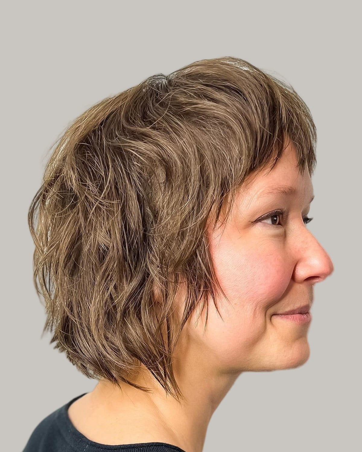 Woman with a brown shaggy bob, seen in profile