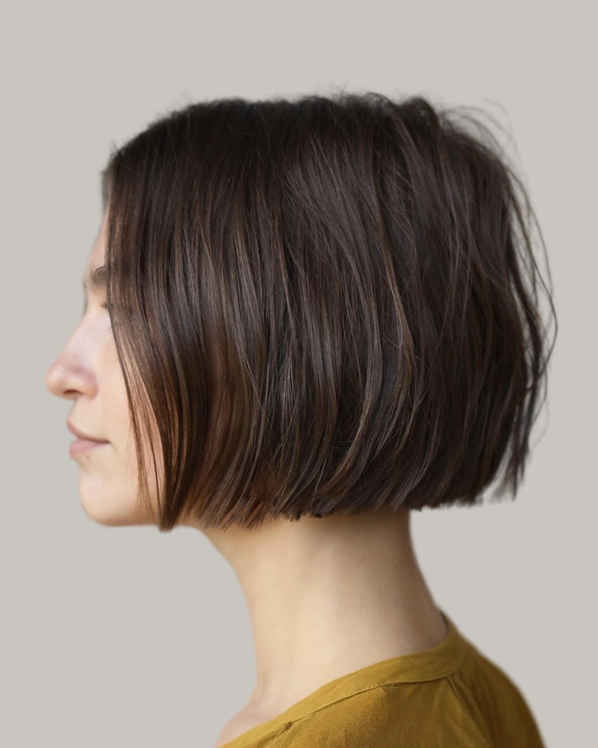 Woman with a dark brown blunt bob at the jaw, seen in profile