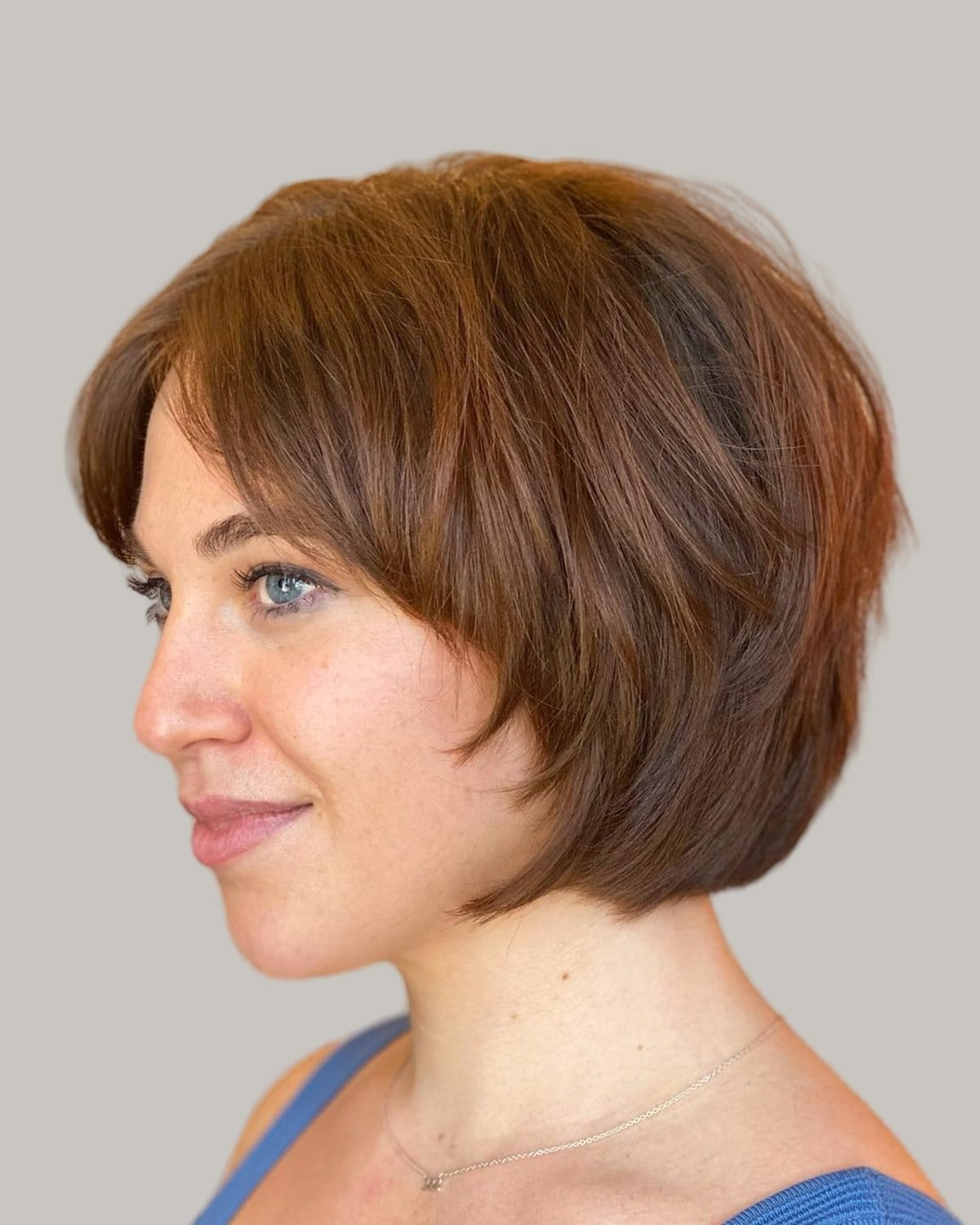 Woman with an auburn short bob and a side-swept fringe, seen in profile