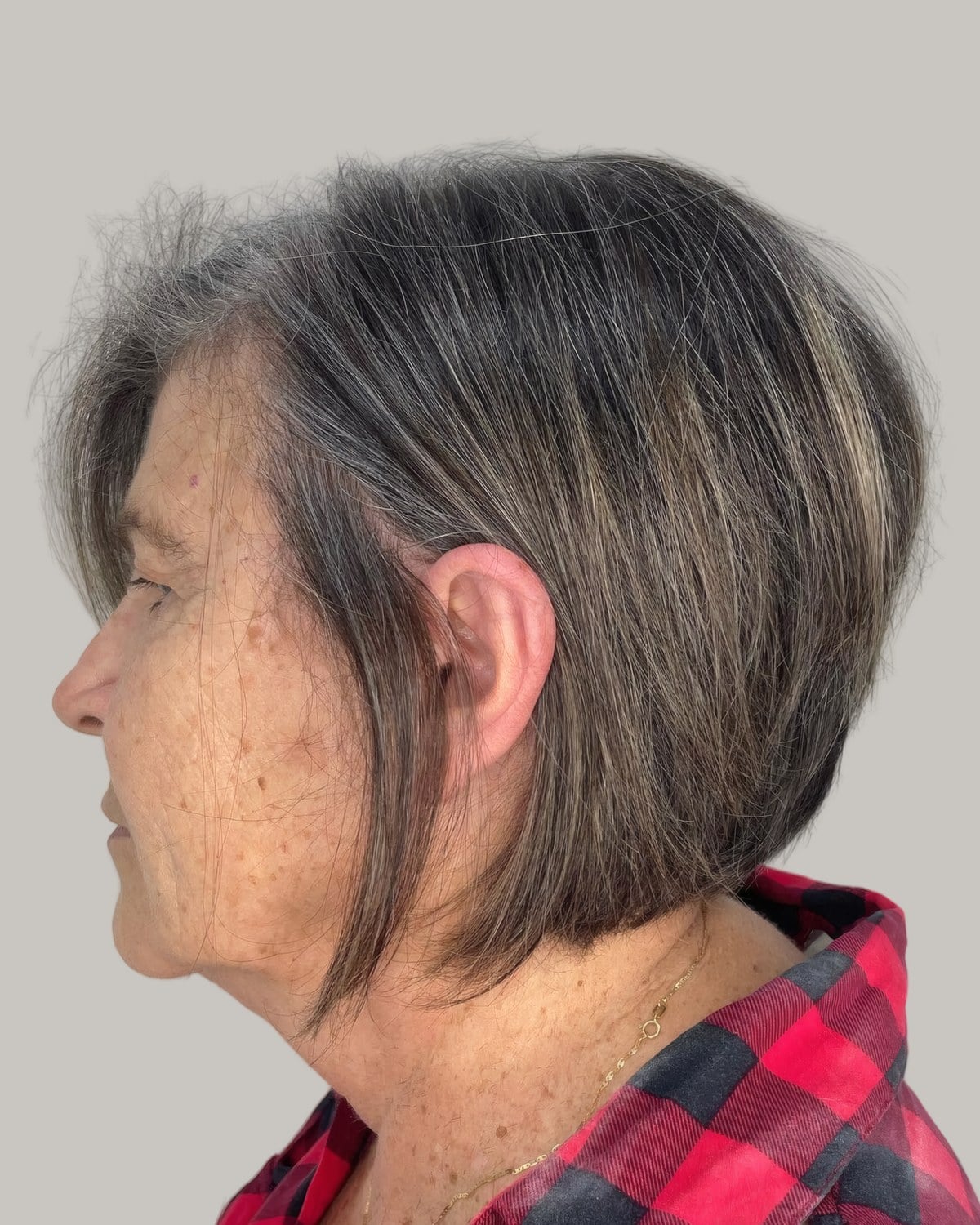 Older woman with a gray and brown short bob, seen in profile