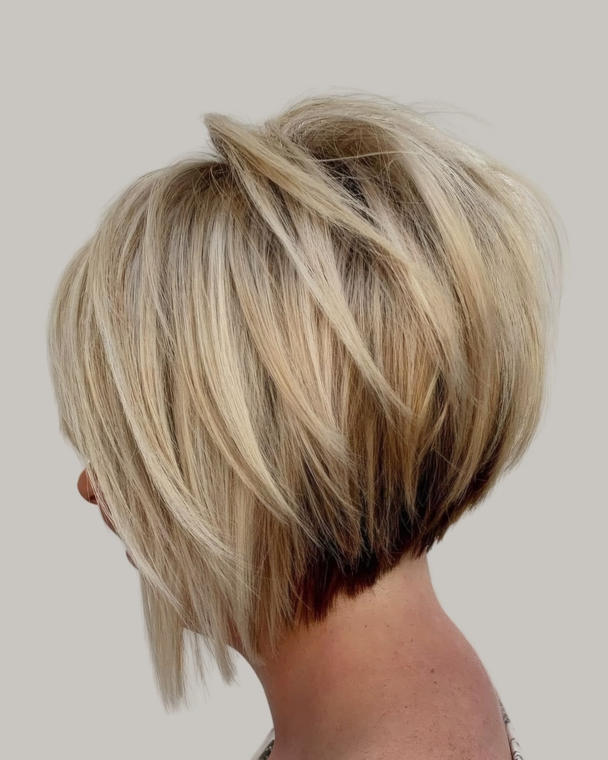 Woman with a blonde stacked bob, seen from behind at an angle