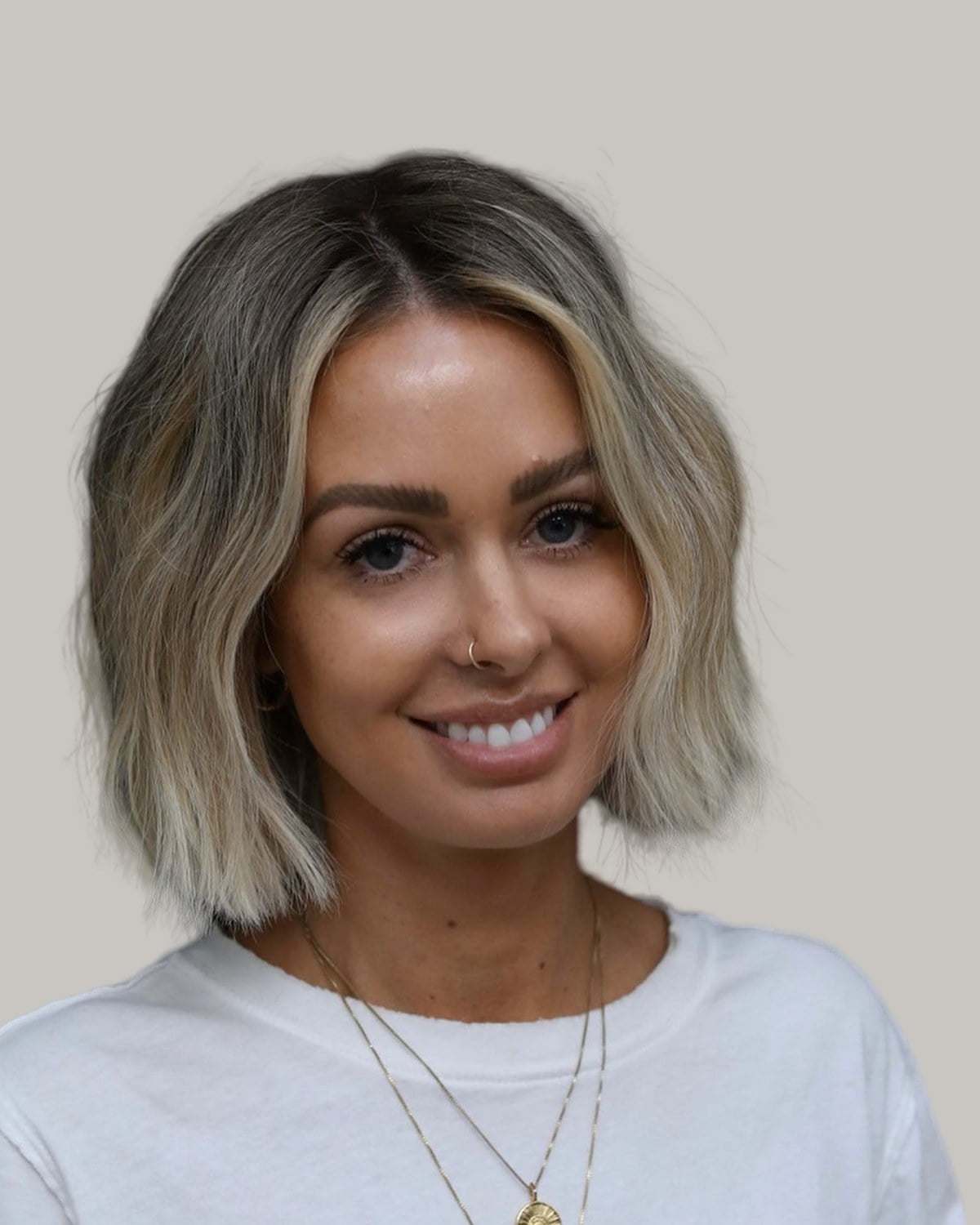 Smiling woman with a blonde lived-in bob and a middle part, facing the camera