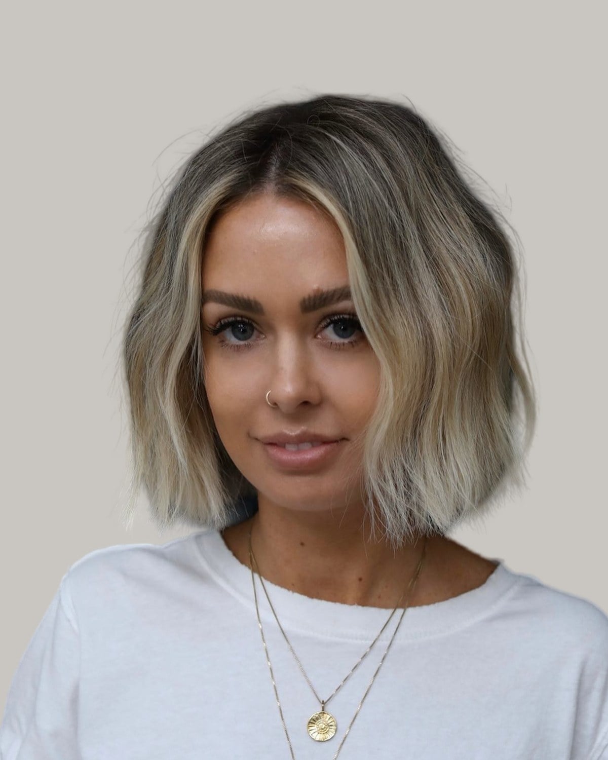 Woman with a blonde lived-in bob and a middle part, in three-quarter view