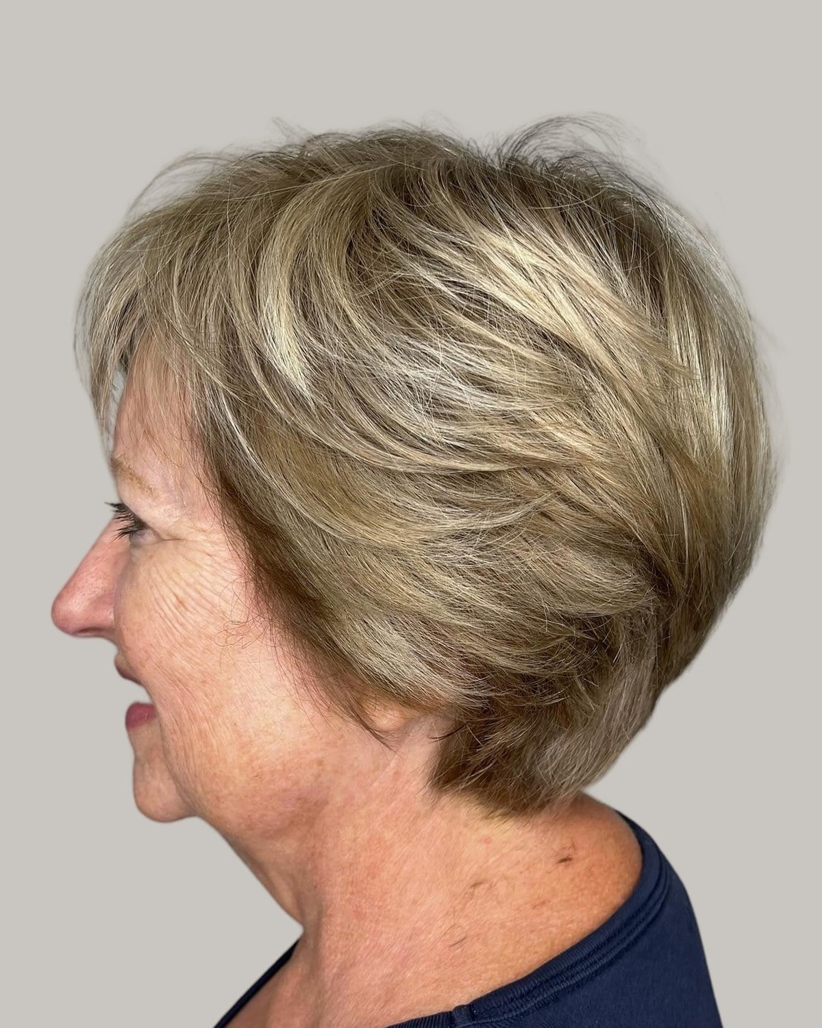 Older woman with a layered blonde short bob, seen in profile