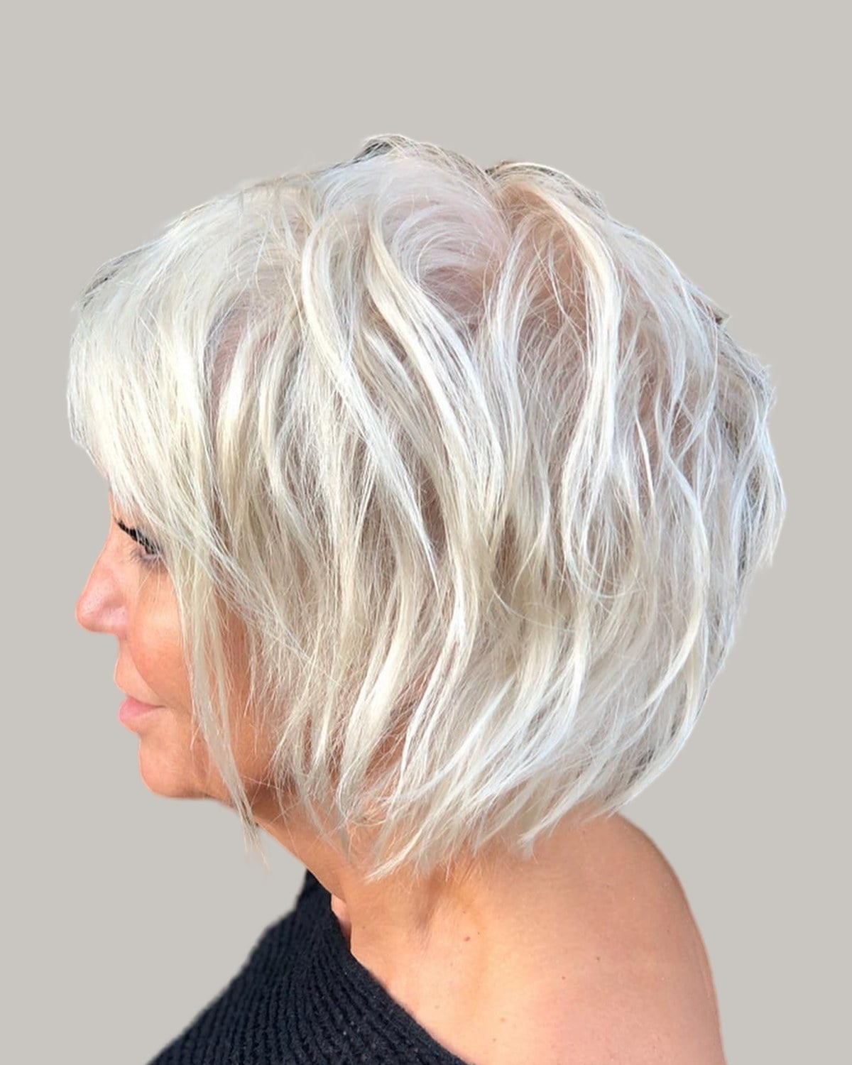 Woman with a white layered bob and a side fringe, seen in profile