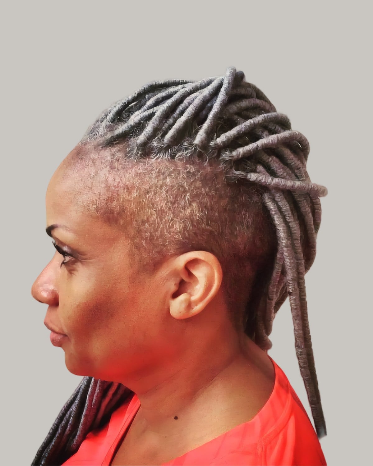 Woman with locs cornrowed up the side into a mohawk, in profile