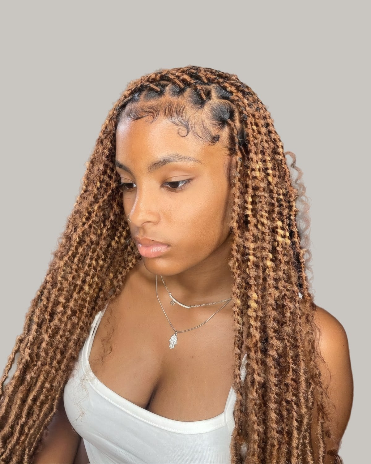 Woman with long honey-blonde curly locs and a center part