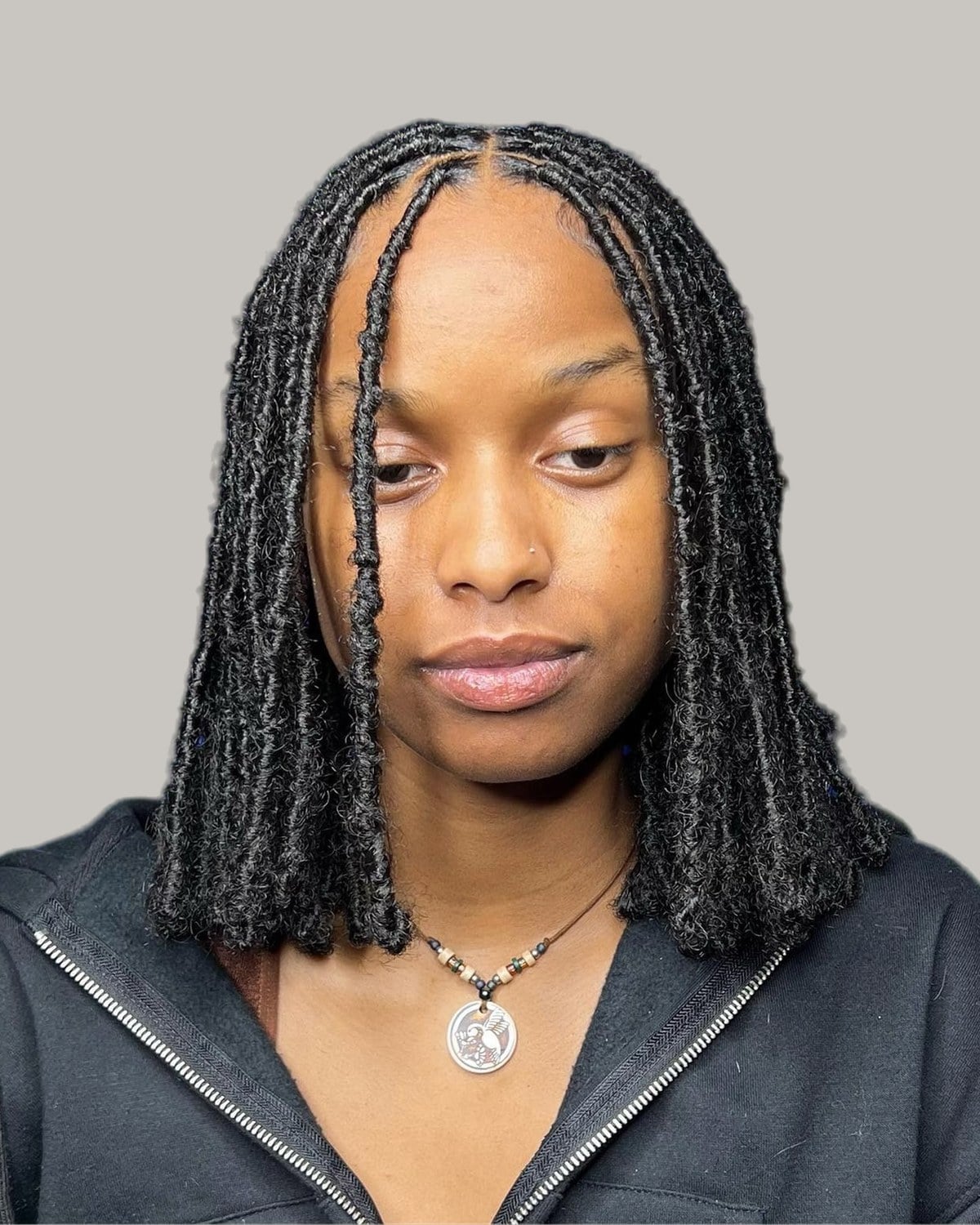 Woman with collarbone-length black faux locs and a center part